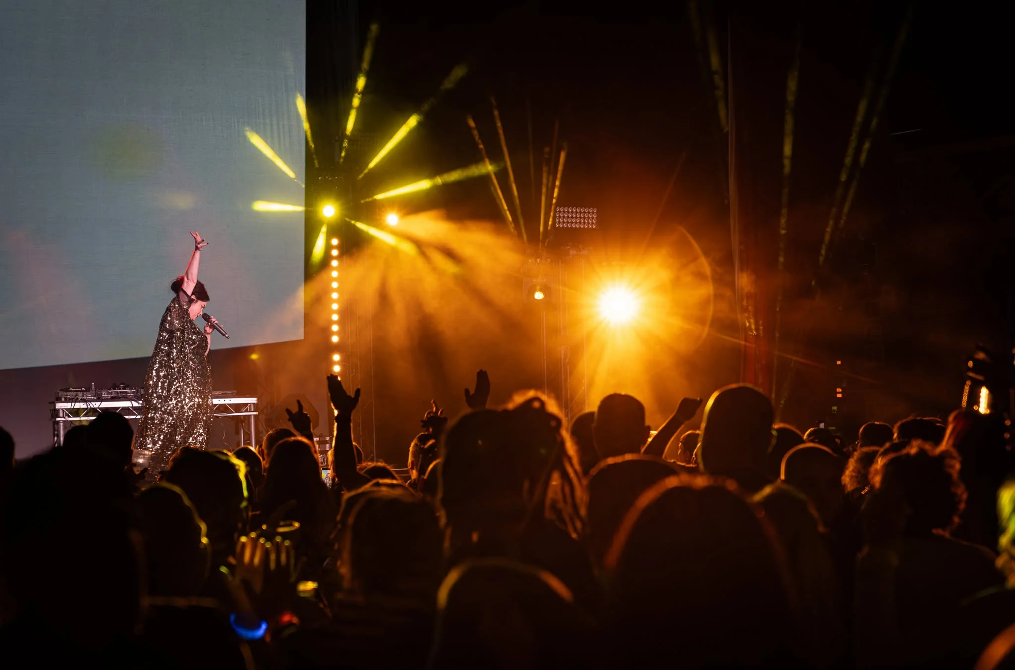 Performer on stage under amber lighting in front of a crowd